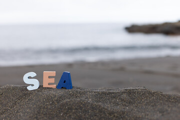 Word sea made of colourful wooden letters stand on the morning beach.