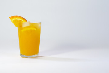 Photo of a glass filled with cold orange juice on a white background with a shadow