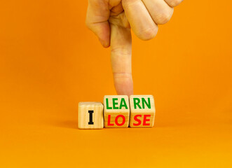 I learn or lose symbol. Concept words I learn and I lose on wooden cubes. Businessman hand. Beautiful orange table orange background. Business and i learn or lose concept. Copy space.