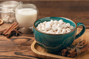 Cup of tasty cocoa drink and marshmallows in blue cup.Spices and marshmallows for winter drinks on brown texture table.Winter hot drink.Hot chocolate with marshmallow and spices.Copy space.