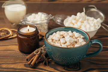 Cup of tasty cocoa drink and marshmallows in blue cup.Spices and marshmallows for winter drinks on brown texture table.Winter hot drink.Hot chocolate with marshmallow and spices.Copy space.