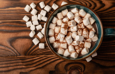 Cup of tasty cocoa drink and marshmallows in blue cup.Spices and marshmallows for winter drinks on brown texture table.Winter hot drink.Hot chocolate with marshmallow and spices.Copy space.