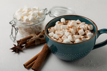 Cup of tasty cocoa drink and marshmallows in blue cup.Spices and marshmallows for winter drinks on white texture table.Winter hot drink.Hot chocolate with marshmallow and spices.Copy space.