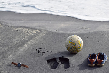 Foot mark and football in a beach. Concept -Recreation at beach