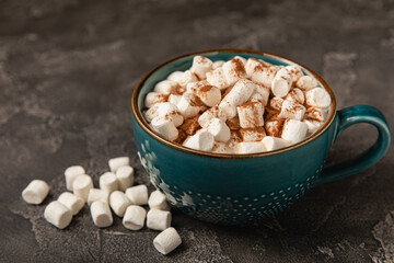 Cup of tasty cocoa drink and marshmallows in blue cup.Spices and marshmallows for winter drinks on black texture table.Winter hot drink.Hot chocolate with marshmallow and spices.Copy space.