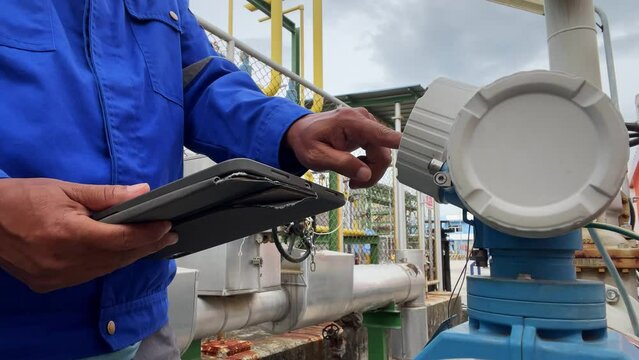 Production engineers inspect industrial equipment at pipeline at factory. Referent holding a tablet with a design sheet. Concept of industry and technology