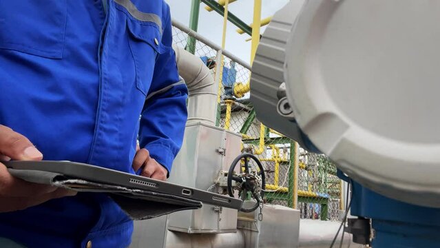Production engineers inspect industrial equipment at pipeline at factory. Referent holding a tablet with a design sheet. Concept of industry and technology