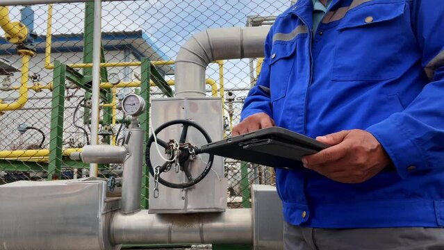 Production engineers inspect industrial equipment at pipeline at factory. Referent holding a tablet with a design sheet. Concept of industry and technology