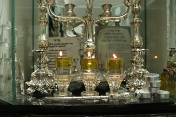 Fototapeta na wymiar Shabbat candles are lit with oil in silver candlesticks. Orthodox Jewish custom on Saturday night before sunset.