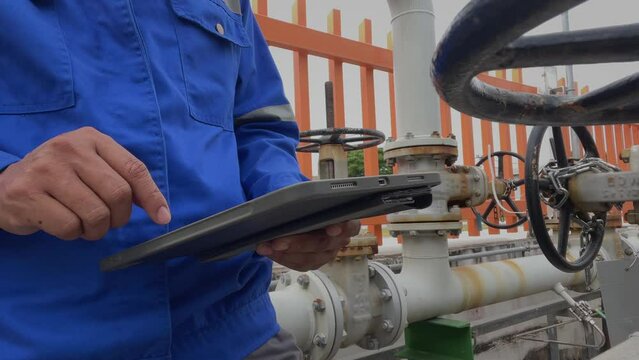 Production engineers inspect industrial equipment at pipeline at factory. Referent holding a tablet with a design sheet. Concept of industry and technology