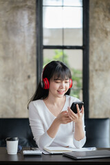 Happy woman is listening music via headset and smartphone at home or office space.