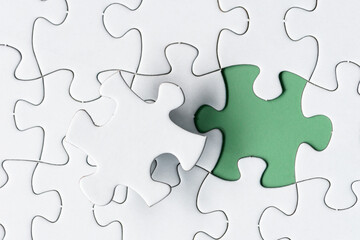 White jigsaw puzzle with missing piece on green background. Copy space.