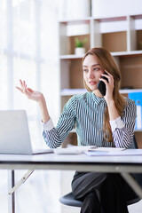 Beautiful young Asian woman work at home with laptop and talking on smartphone and smiling. Asian Female working on computer and using cell mobile phone while sitting at home