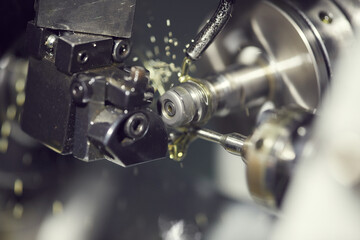 Close-up of cutting fluid pouring on drill tool of lathe machine during processing detail