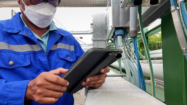 Production engineers inspect industrial equipment at pipeline at factory. Referent holding a tablet with a design sheet. Concept of industry and technology