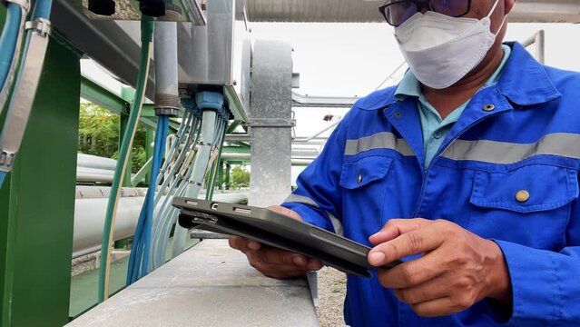 Production engineers inspect industrial equipment at pipeline at factory. Referent holding a tablet with a design sheet. Concept of industry and technology