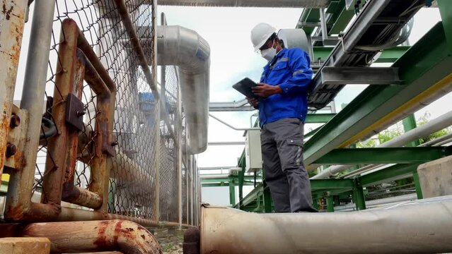 Production engineers inspect industrial equipment at pipeline at factory. Referent holding a tablet with a design sheet. Concept of industry and technology