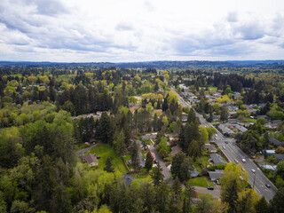 Obraz premium Shooting from a drone. A small green city with developed infrastructure. A mountain range is visible on the horizon. Cloudy sky. Construction, planning, tourism, ecology.