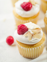 Close-up. Light summer dessert - muffins with cream, fresh raspberries and almonds. Isolated on white background. Birthday, anniversary, banquet, picnic. Banner, invitation.