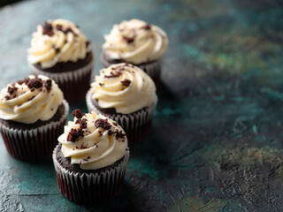 Chocolate cupcakes with cream and grated chocolate. Isolated on a dark background. Holiday, birthday. There are no people in the photo. There is free space to insert.