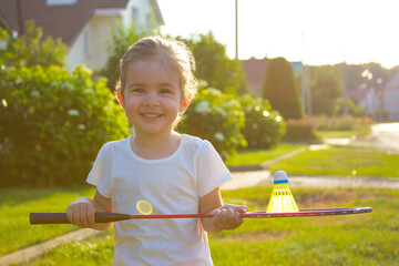 Positive child girl sport racket tennis badminton summer lawn at home 