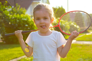 Positive child girl sport racket tennis badminton summer lawn at home 