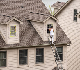 Masking tape holding plastic covering in place on windows prior to spraying paint on home
