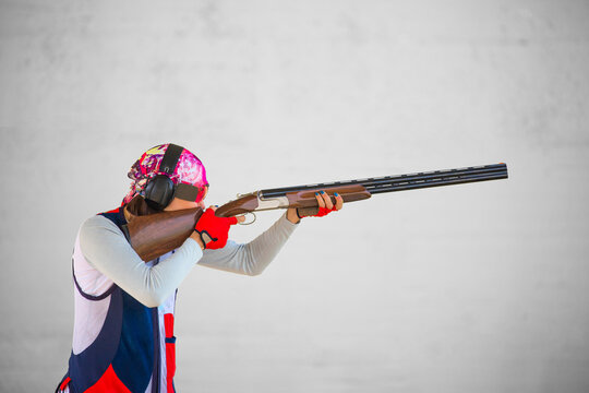 Clay pigeon shooting. An athlete shoots a gun at moving targets isolated on a green background, sport gun shooting, with a place for text, clay pigeon shooting.