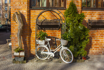 Fototapeta na wymiar White bike standing on a place next to the restaurant at old town in Gdansk, Poland 
