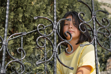 A child behind a wrought-iron fence looks into the camera.