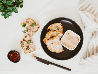 Fresh homemade chicken liver pate on toast with parsley and spices, homemade bread on table
