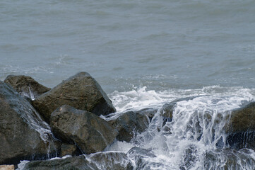 Storm on the seashore. The waves hit the rocks and create foam.