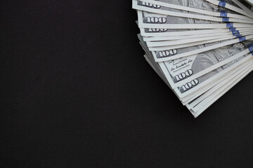 Top view of bundle of 100 dollar bill on black background. Business concept with copy space