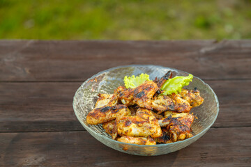 Chicken wings in a transparent plate on a wooden table.