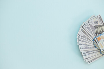 Top view of bundle of 100 dollar bill on blue background. Business concept with copy space