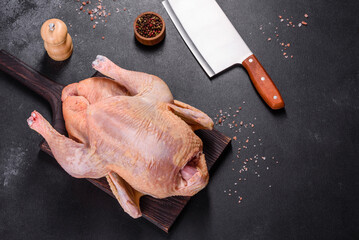 Raw turkey or chicken with salt, spices and herbs on a wooden cutting board. Preparing a festive table