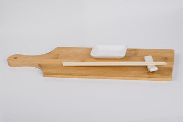 close-up, on a white background, on a wooden cutting board, chopsticks for Japanese sushi and a container for sauce