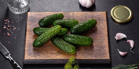 Delicious fresh cucumbers with garlic, salt, spices and herbs on a wooden cutting board