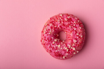 Donut on a pink background.Strawberry donut with pink icing and sprinkles on a paper...