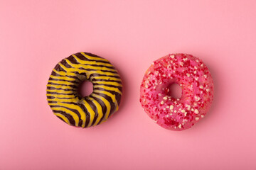 Donuts on a pink background.Chocolate and strawberry donut with yellow and pink icing on a paper background.Colorful minimalism concept.Junk food.Sweets.Copy space.Flat lay.Place for text.