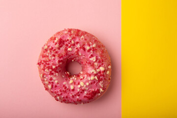 Donut on a pink background.Strawberry donut with pink icing and sprinkles on a paper background.Colorful minimalism concept.Junk food.Sweets.Copy space.Flat lay.Place for text.