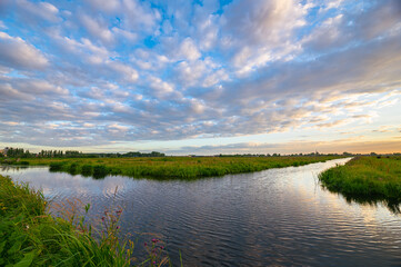Altocumulus sheep clouds over water-filled ditches and grasslands in the Dutch countryside