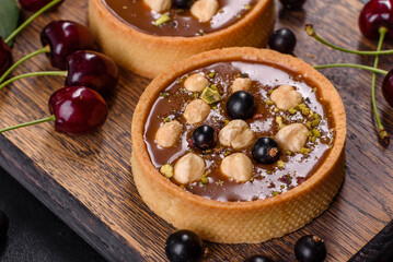 Delicious fresh nougat and nut tart with fresh berries on a wooden cutting board