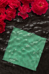 Red roses with a paper sheet floating in black water. Minimal flower background.