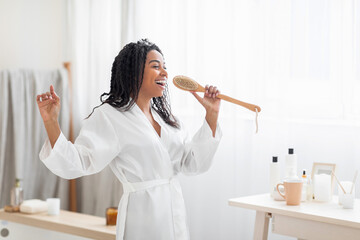 Happy Young Black Woman Singing In Bathroom, Using Body Brush As Microphone
