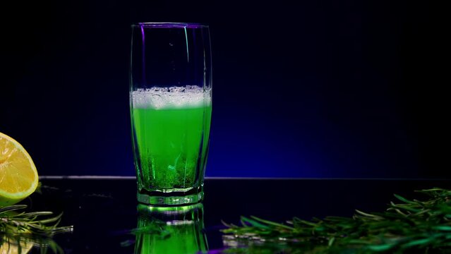 Blue background with a drink . Stock clip . A bright background on which tarragon is poured and a lemon with a fir branch lies next to it.