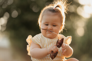 A close portrait of a pretty female toddler in yellow clothes who is enthusiastically playing with...