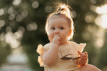 A close portrait of a female toddler in yellow clothes who is enthusiastically playing with...