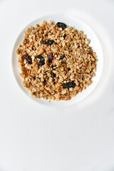 Muesli with nuts and raisins on a white plate