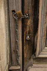 Old wooden door closed with chain and padlock